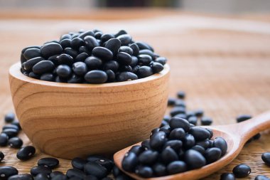 Masa üzerinde ahşap kase ve kaşık ham siyah fasulye.