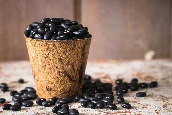 Black beans in Bio cup on wooden background.