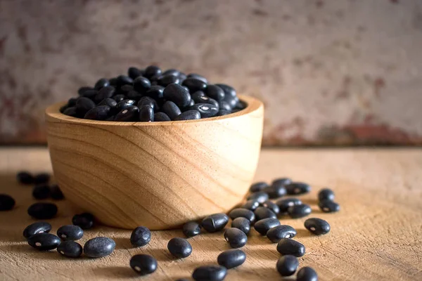 Frijoles negros en cuenco de madera en tabla de cortar . —  Fotos de Stock