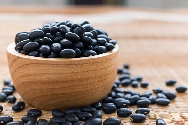 Black beans in wooden bowl set on cutting board.