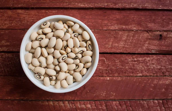 Black eyed beans in bowl on wooden background