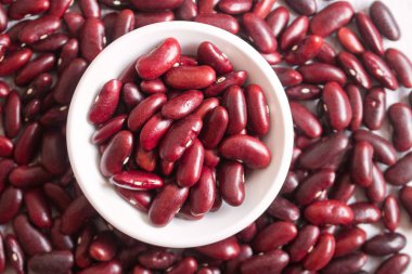 Ahşap arka planda beyaz kase de Kırmızı fasulye.