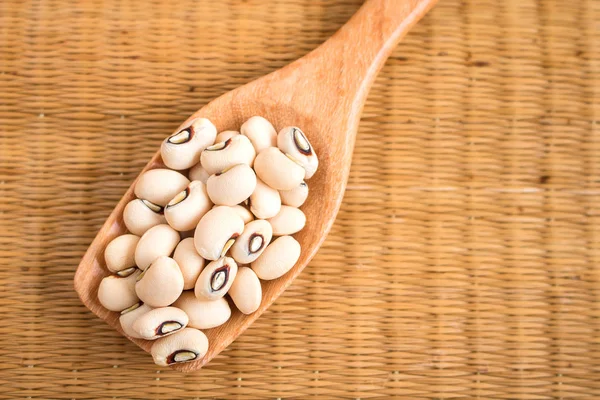 Kacang bermata hitam dalam sendok kayu di tikar buluh . — Stok Foto