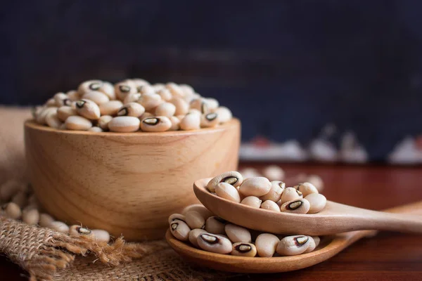Black-eyed beans in wooden bowl on a rustic table.