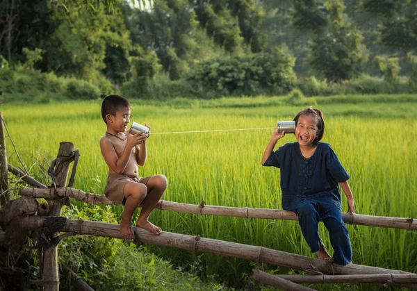 Niños rurales hablando en una lata de teléfono . — Foto de Stock