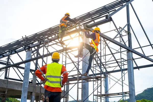 Engineer technician watching team of workers on high steel platf