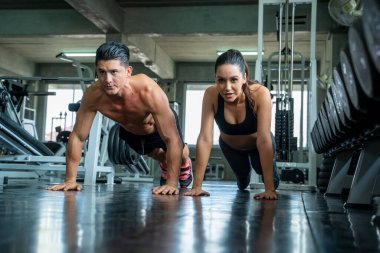 Antrenörle kadın egzersizi, genç çift spor salonunda birlikte çalışıyor..