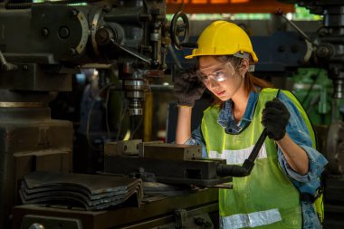 Üniformalı kadın teknisyen fabrikadaki makineleri kontrol ediyor..