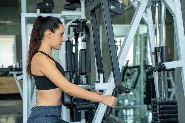 Woman exercising hard on gym,Fitness woman training with bare chest exercising on machines during workout in modern gym.