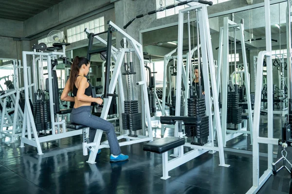 Woman exercising hard on gym,Fitness woman training with bare chest exercising on machines during workout in modern gym.