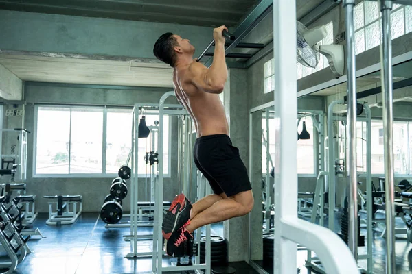 Muscular man workout doing pull ups on bar in gym,Man working out in a fitness club.