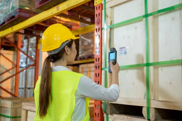 Büyük depo, lojistik ve ihracat konseptinde lazer barkod tarayıcı ile paket ürünlerini tarayıp tarayan işçiler.
