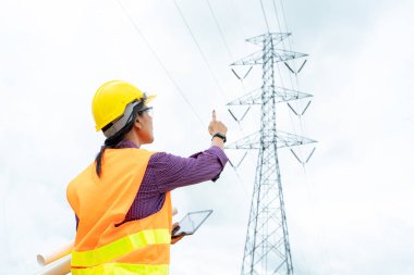 Elektrik mühendisi yüksek voltaj kulesinin yakınındaki konumu kontrol ediyor..