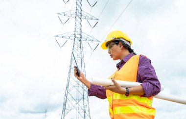 Elektrik mühendisi, yüksek voltaj direği güç transmisyonunu kontrol etmek için tablet kullanıyor.