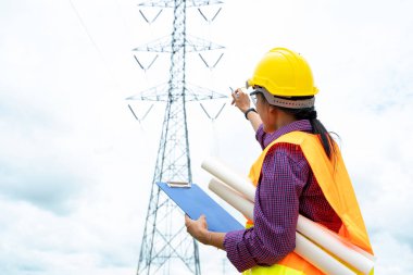 Elektrik mühendisi yüksek voltaj kulesinin yakınındaki konumu kontrol ediyor..