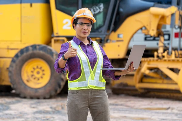 女工程师戴着头盔 在建筑工地 建筑工地 建筑机械 推土机 挖掘场展示大拇指 — 图库照片
