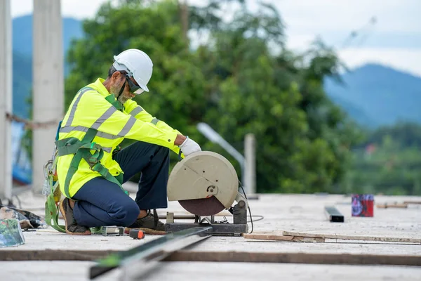 Industrial construction engineer cutting steel using angle mitre saw at building site.