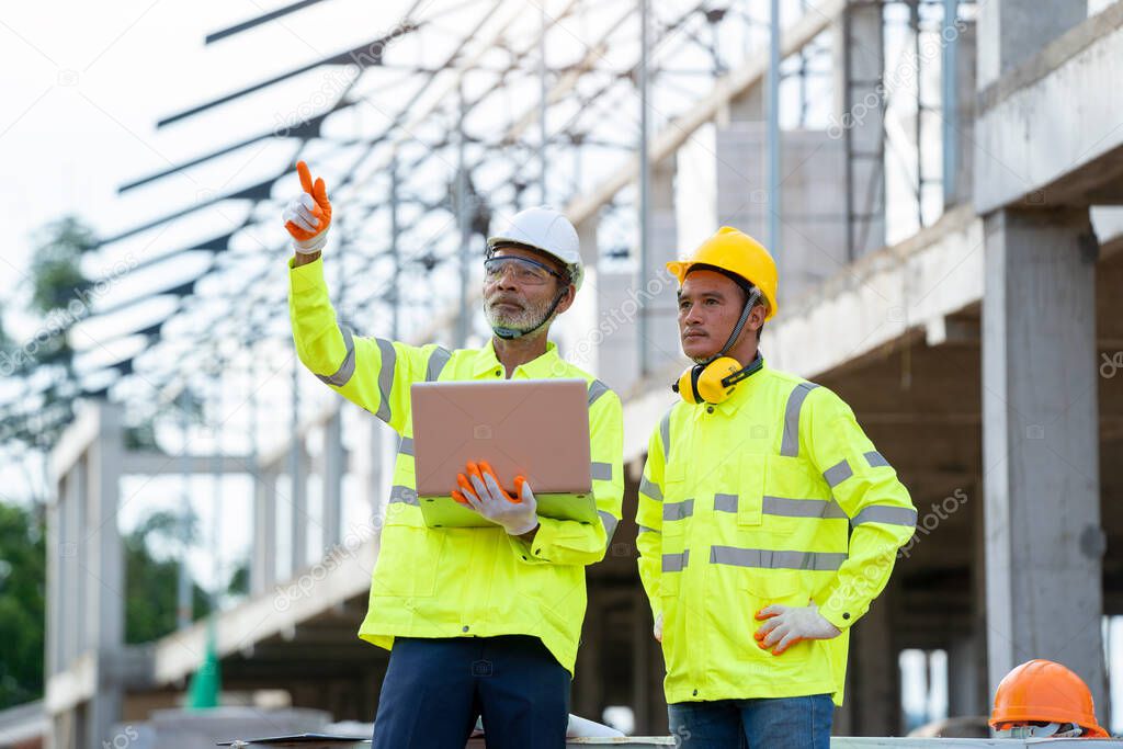 Engineer discussing with architect use laptop about project in building construction site