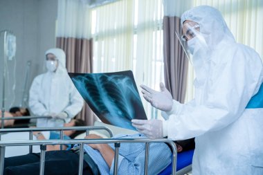 Tehlikeli madde koruma giysisi giyen doktor hastanedeki hasta Coronavirus 'un röntgen filmi için eldiven takıyor..