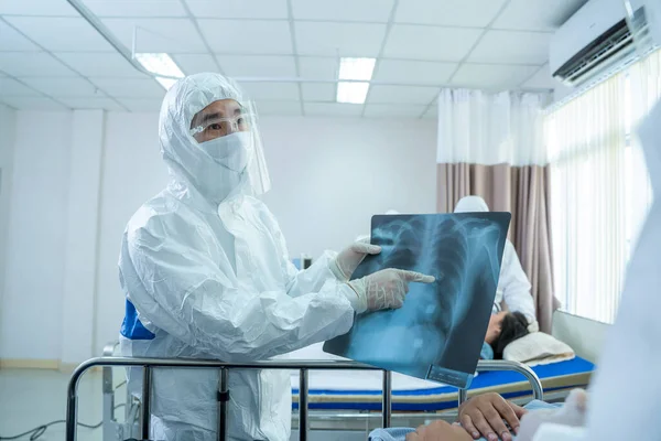 Doctor in hazmat PPE protective clothing wear medical rubber gloves holding an X-ray film for an infected patient at hospital,Coronavirus has turned into a global emergency.