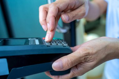 Kredi kartı geçiş makinesinde yazan kadın, ödeme süreci.