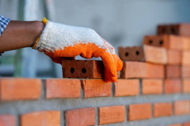 Tuğla ustası endüstriyel işçiler yeni evin dış duvarına tuğla döşüyorlar..