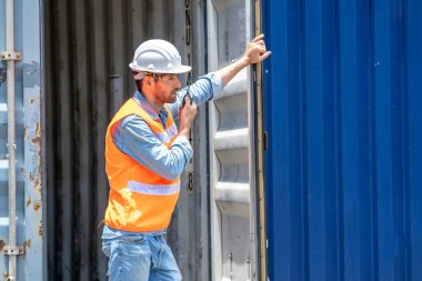 Ustabaşı konteyner deposundaki yükleme konteynırını kontrol etmek için telsizle konuşuyor..