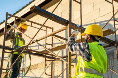 Yüksek mevkide çalışırken emniyet kemeri takan inşaat işçisi inşaat halindeki konut kavramı.