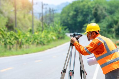 Yolda teodolit ulaşım ekipmanlarıyla çalışan bir mühendis..