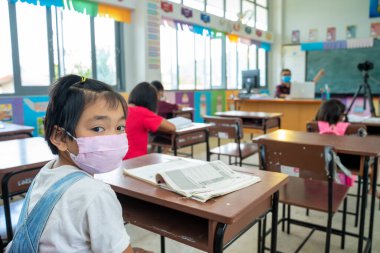 Onu virüsten korumak için tıbbi maske ya da cerrahi maske takan bir grup öğrenci sınıfta, Covid-19 ve Coronavirus enfeksiyonundan korunuyor..