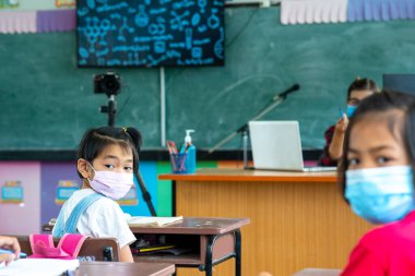 Onu virüsten korumak için tıbbi maske ya da cerrahi maske takan bir grup öğrenci sınıfta, Covid-19 ve Coronavirus enfeksiyonundan korunuyor..