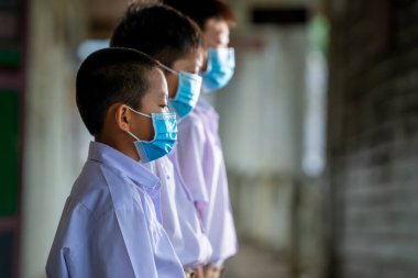 Covid-19 'a karşı korunmak için koruyucu maske takan Asyalı öğrenci, ilkokulda ayakta duruyor..