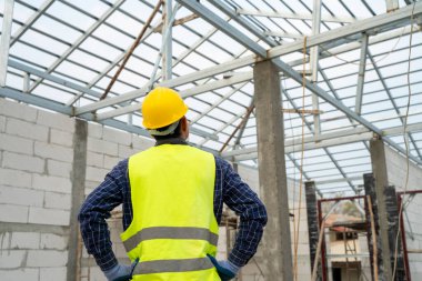 İnşaat alanındaki inşaat işçisinin portresi, yeni evde çalışan sıkı şapkalı inşaat işçisi..