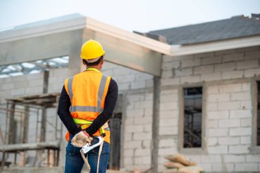 Ev inşaatında çalışan çelik yelek ve sarı kask giyen inşaat mühendisi..