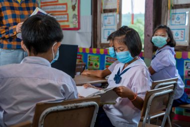 Covid-19 'a karşı korunmak için koruyucu maske takan okul çocukları sınıfta, eğitimde, ilkokulda.