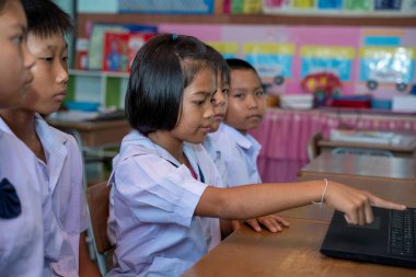 Bir grup Asyalı ilkokul öğrencisi sınıfta dizüstü bilgisayar kullanmayı öğreniyor, Asya Öğrenci Eğitimi Konsepti.