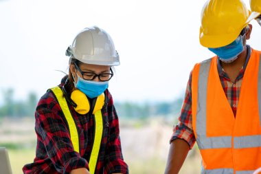 Mimarlar inşaat alanındaki inşaat projesini mühendis ile tartıştılar.