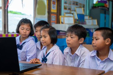 İlkokul öğrencileri sınıfta bilgisayar, eğitim, öğrenme ve insan kavramına bakıyorlar..