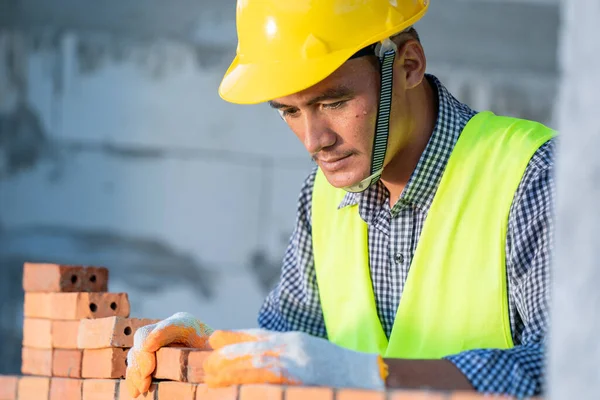 Industrial bricklayer installing bricks on construction site,Bricklayer worker installing brick masonry.