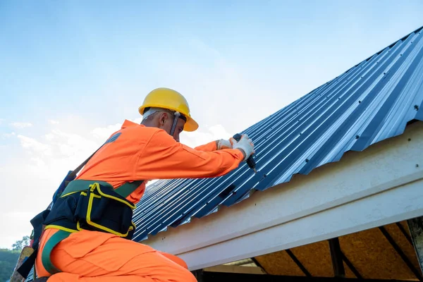 プロの技術労働者は 金属シートと新しい屋根に使用される新しい屋根 屋根のツール 電気ドリルをインストールします — ストック写真
