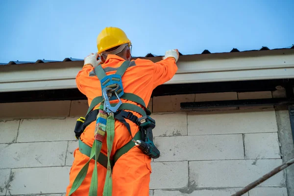 Working at height equipment,Construction worker wearing safety harness belt during working on roof structure of building on construction site.