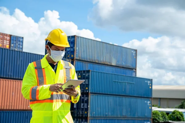 Young worker man with digital tablet at container terminal port,Business Logistics import export shipping concept.