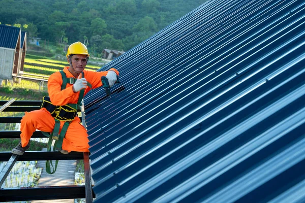 Roofer worker in protective uniform wear and gloves installing new roof,Concept of residential building under construction.