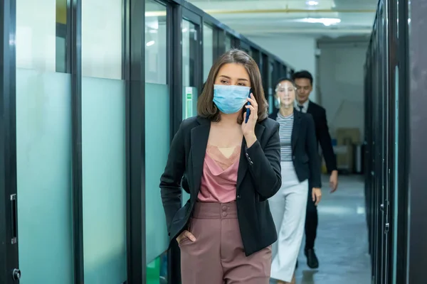Business workers wearing medical facial mask working as of social distancing policy in the business office during new normal change after coronavirus or post covid-19 outbreak pandemic situation.