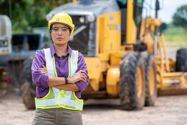 建筑工地站在一辆推土机卡车旁的女土木工程师或戴黄色头盔的建筑师 — 图库照片