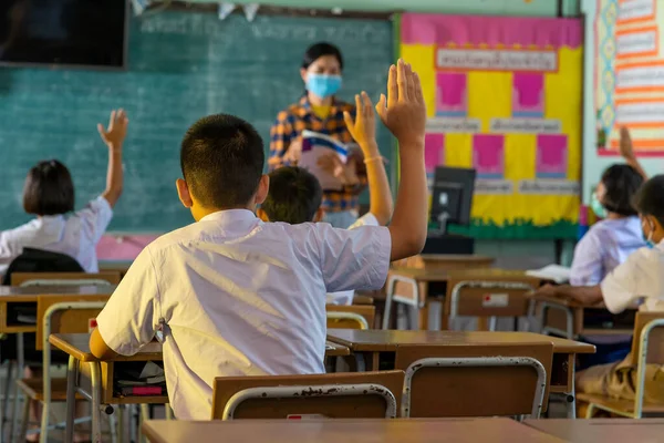 Covid-19 karantina ve tecritten sonra ilkokuldaki sınıfta öğrenciler ve öğretmeni koruyucu maskeler takıyor..
