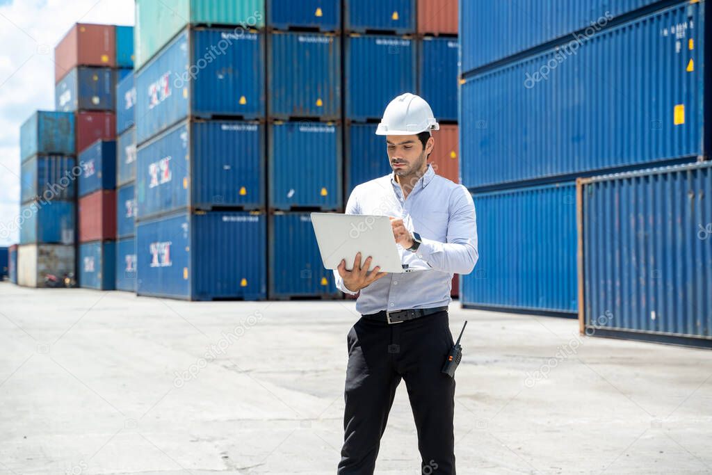 Businessman standing and using walkie talkie checking stock into container for loading in shipping port.