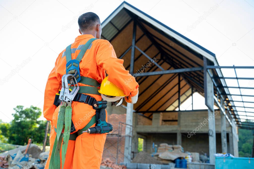 Construction worker wearing safety harness and safety line working at high place work at building site,Concept of residential building under construction.