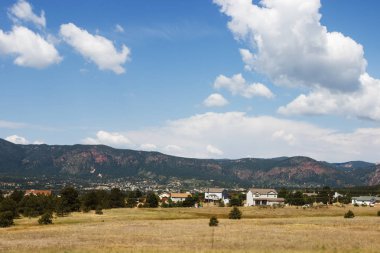 Doğal dağlar, yaz güneşli bir günde derin gökyüzü beyaz bulutlar ile temizleyin. Dağlar eteğinde küçük Amerikan kentlerinin bulunduğu evler. Colorado, ABD.