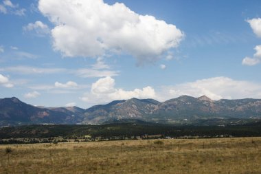 Doğal dağlar, yaz güneşli bir günde derin gökyüzü beyaz bulutlar ile temizleyin. Dağlar eteğinde küçük Amerikan kentlerinin bulunduğu evler. Colorado, ABD.